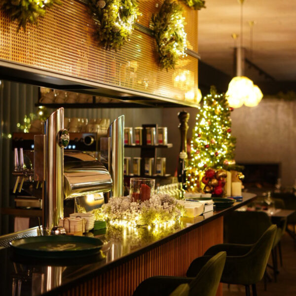 Weihnachtlich dekorierte Bar mit Lichtern, einem kleinen Weihnachtsbaum und festlichen Kränzen an der Wand.