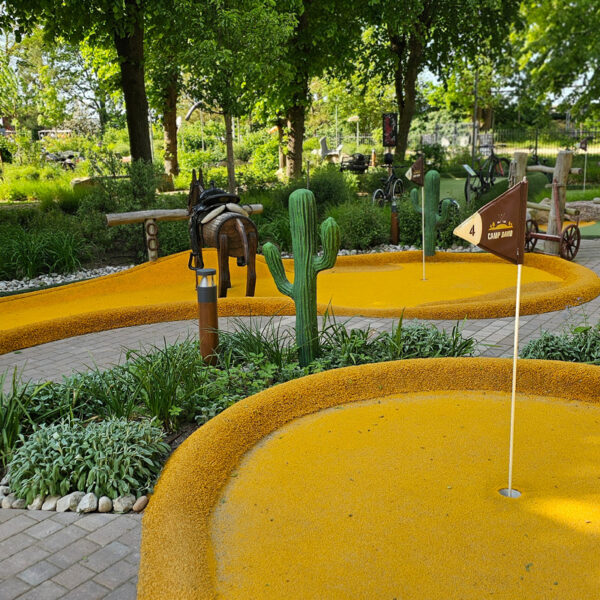 Minigolfplatz im Camp David Abenteuerpark in Boltenhagen mit gelbem Sand, Cactussen und Holzelementen.